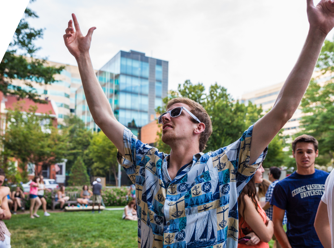 student raising arms in university yard