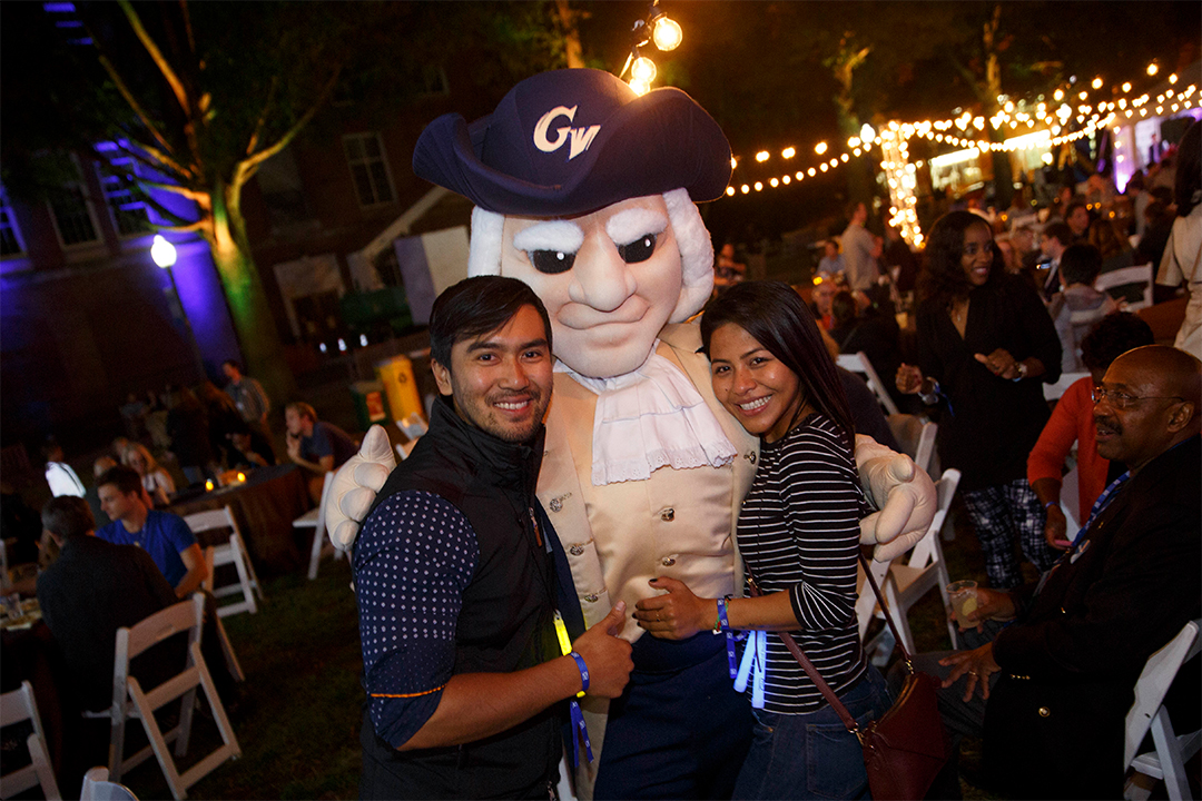 Male and female alum posing with mascot George during Alumni Weekend event