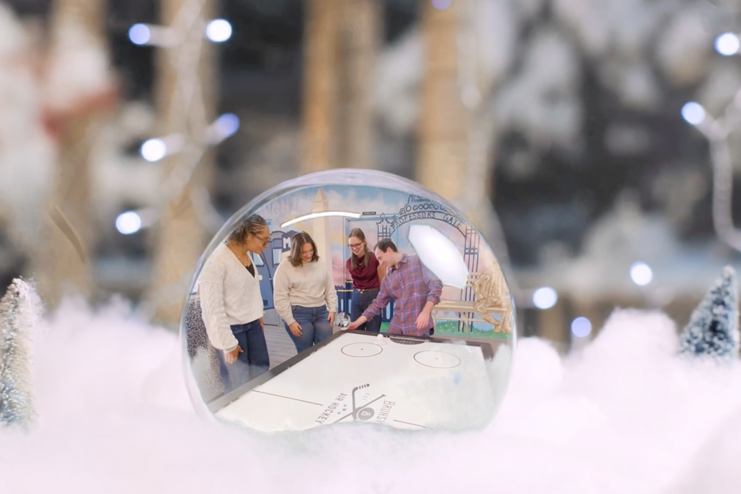 Still from the GW Holiday video of a snow globe with people inside of it. 