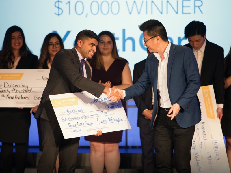 People hold large checks and shake hands