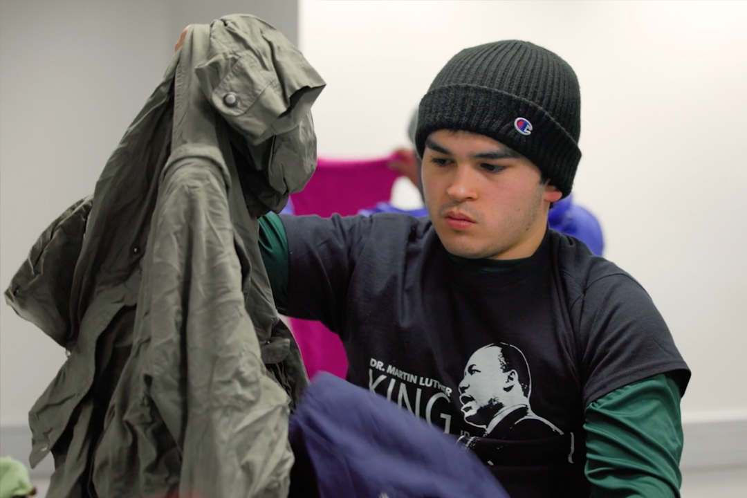 Male student sorts through clothing as a part of an activity for Martin Luther King Jr. Day of Service and Leadership